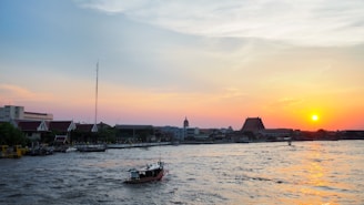 A serene sunrise over a quiet Shanghai river, with traditional boats gently floating.