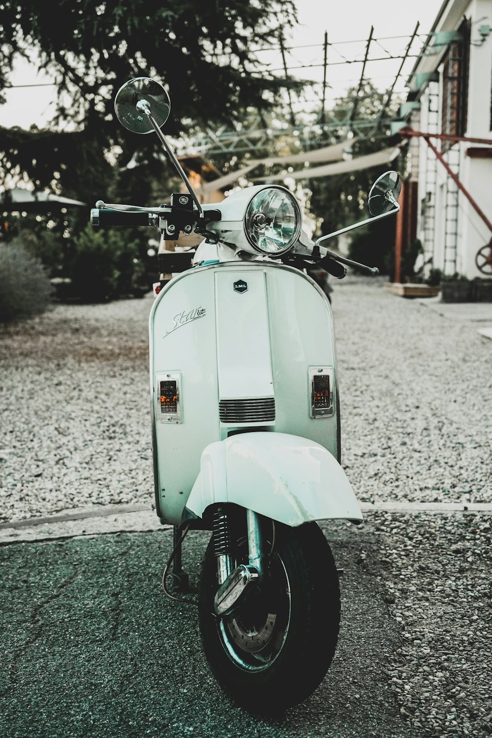 white motor scooter parked standing on pavement