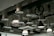 A ceiling with an industrial design featuring various hanging light fixtures and exposed ductwork. The ducts are covered with a textured material, and there are also black metal pulleys and hooks accentuating the design.