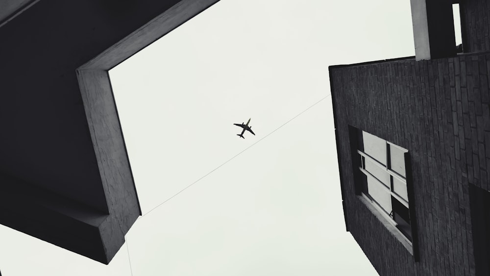 grayscale photography of buildings showing airplane on skies