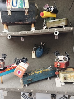 A collection of vintage-inspired robot sculptures crafted from repurposed metal objects, including cameras, tins, and mechanical parts. Each sculpture is creatively assembled with attention to detail, featuring elements like dials, knobs, and colorful labels.