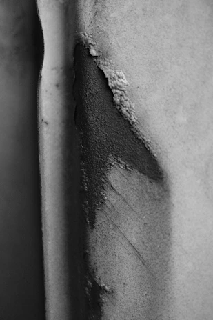 A wide, high-contrast close-up of rough, cracked paint texture revealing deep shadows and highlights.