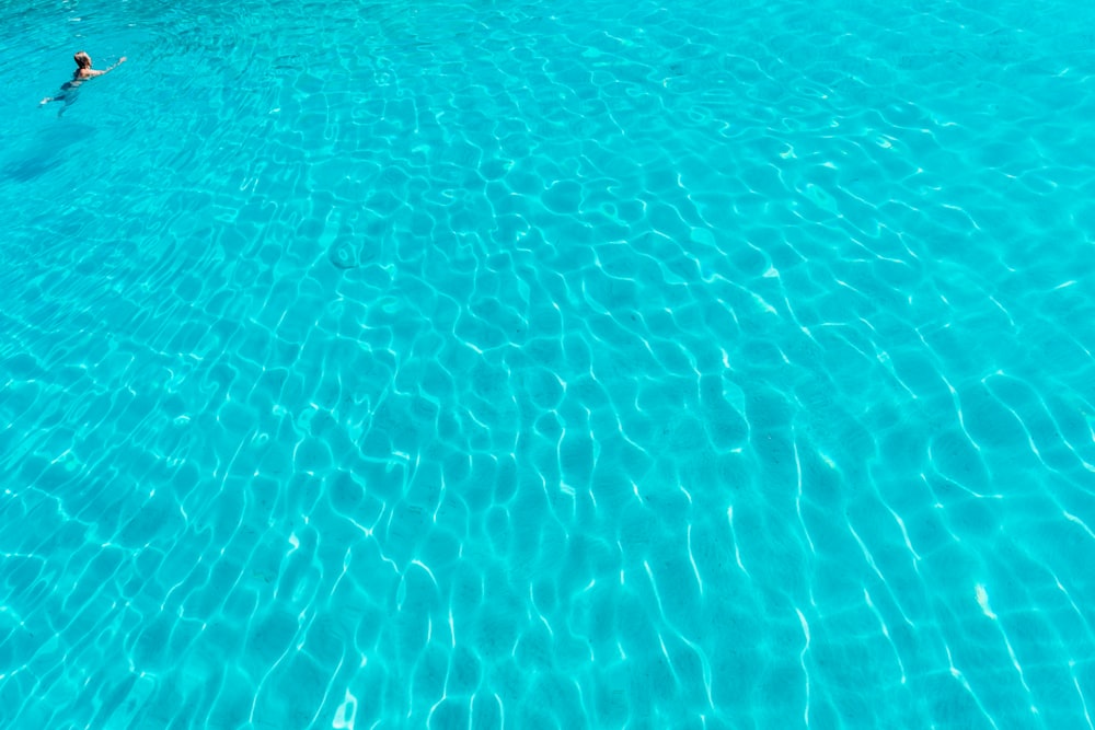 a man is swimming in a pool with blue water