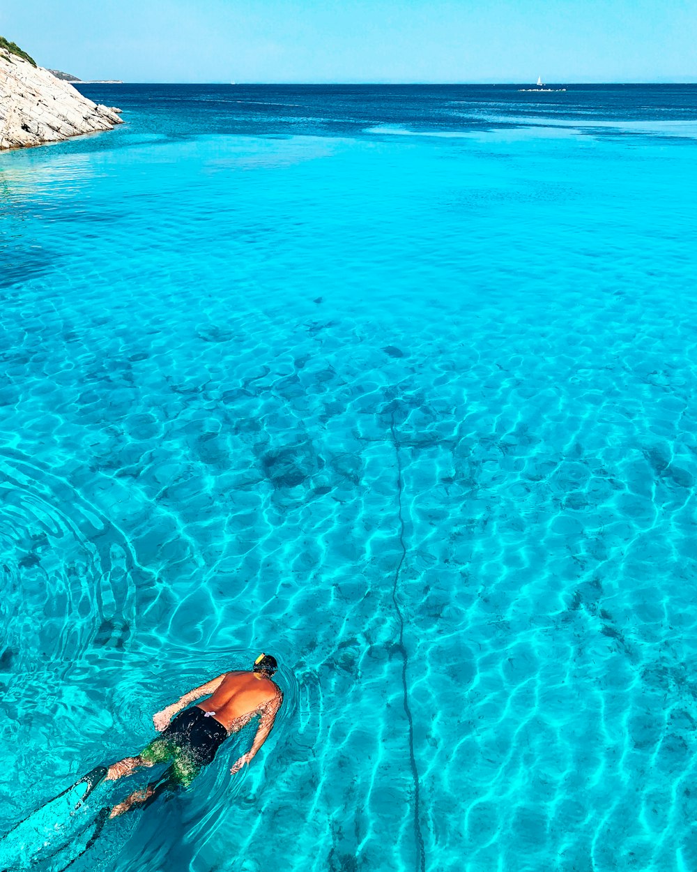 a man is swimming in the clear blue water