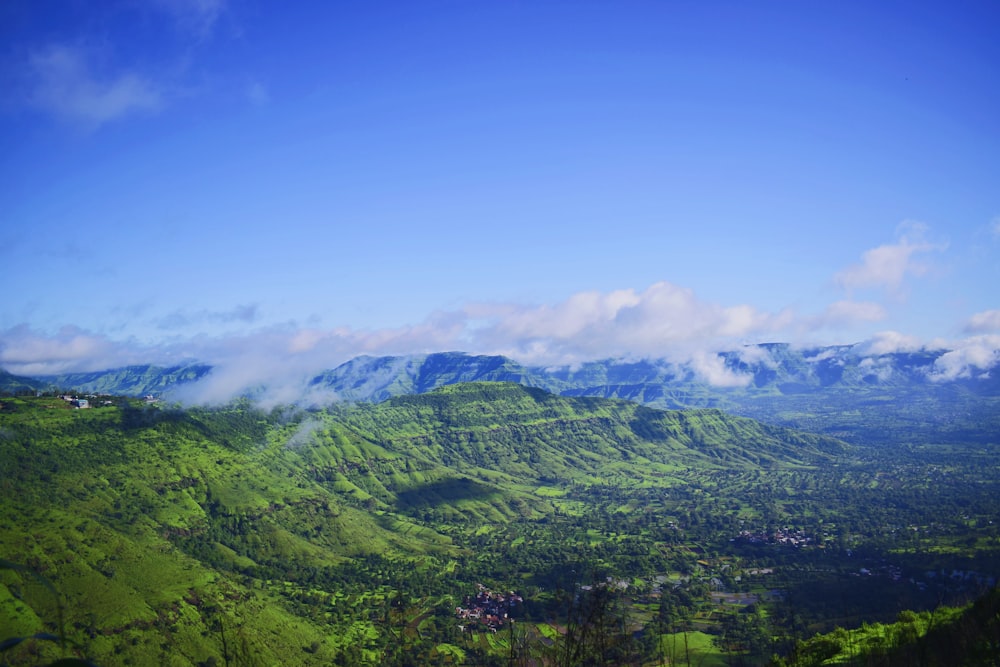 green mountain under white clouds and blue sky during daytime