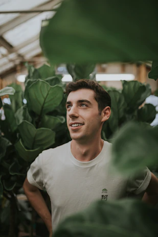 Smiling customer standing beside industrial equipment with lush greenery in the background.