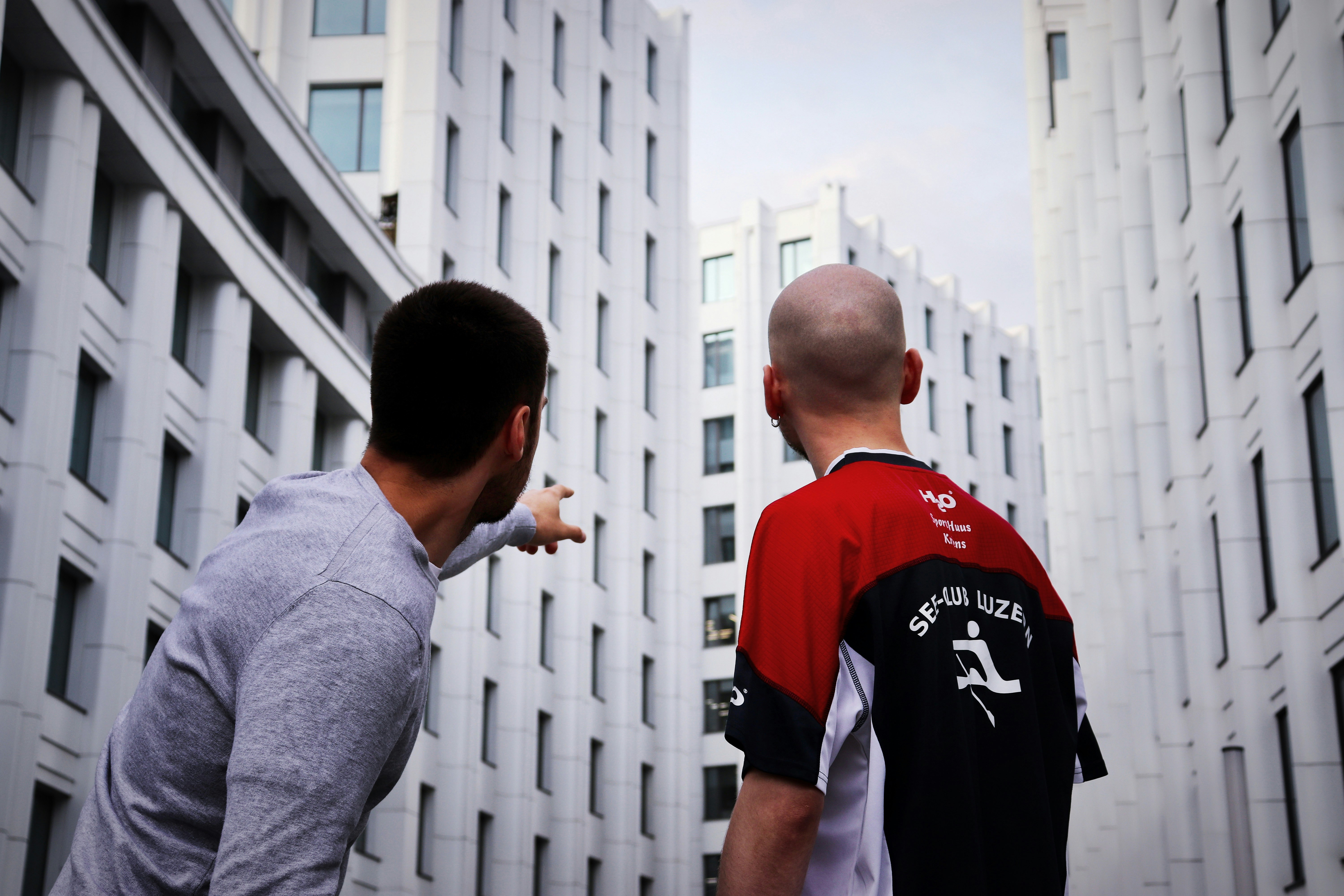 two men standing near white building during daytime, 