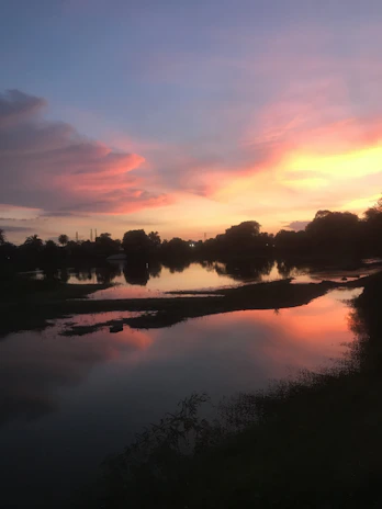 A serene Amazon river at sunset with vibrant orange and purple skies reflecting on the water.