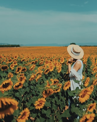 photography of woman standing near sunflower field during daytime