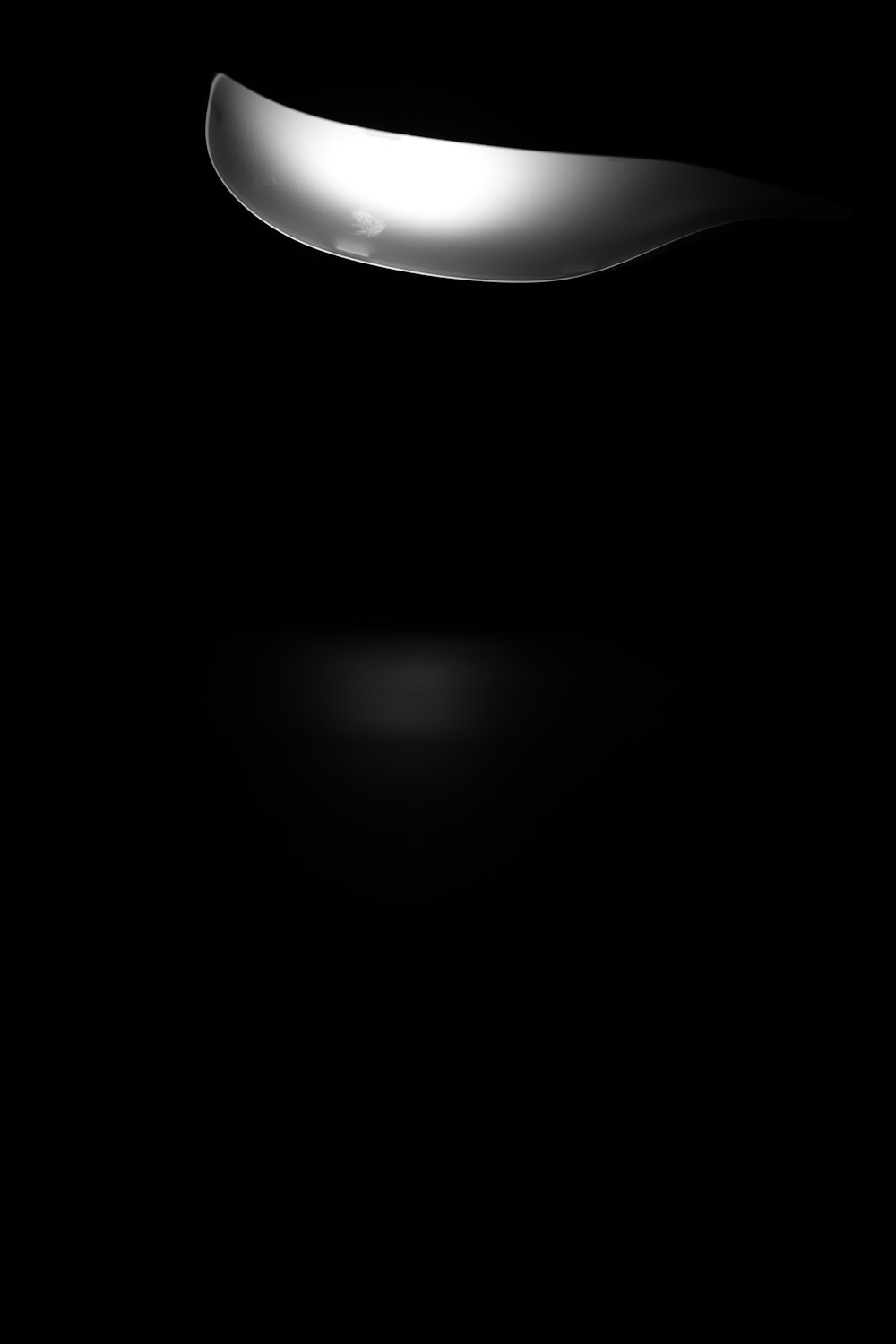 a black and white photo of a spoon in the dark