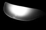 Close-up of a matte black spoon with a smooth, modern design placed beside a small potted succulent.