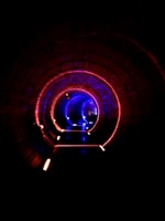 A circular, arched tunnel illuminated with vibrant red and blue LED lights along the sides, creating a futuristic and mysterious ambiance. The tunnel is dark with a focus on the glowing lights, giving a sense of depth and perspective.