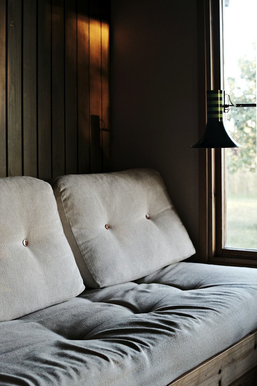 tufted gray sofa near window