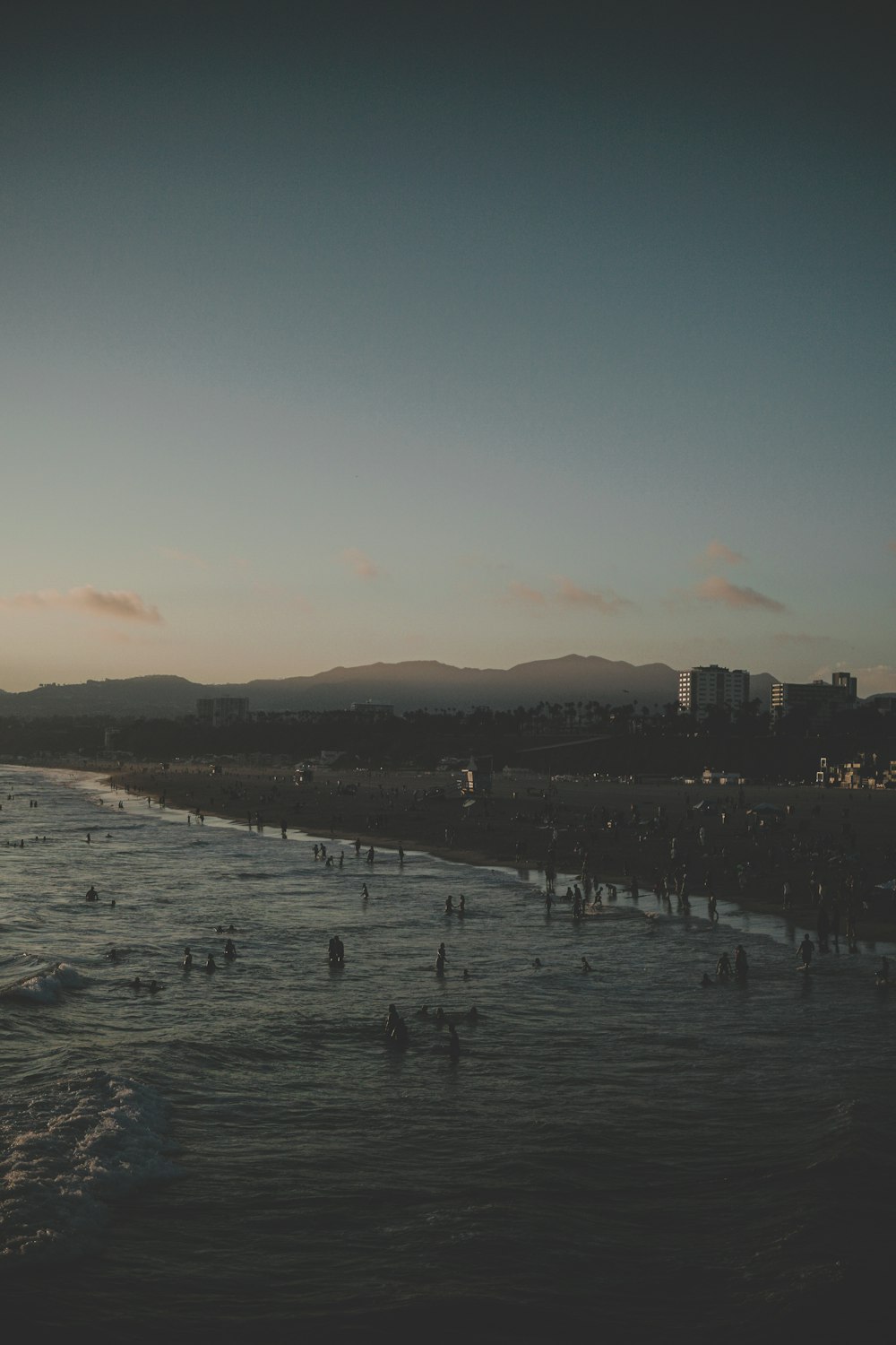 people at the beach under grey sunset sky