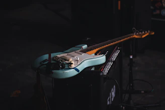 Electric guitar resting on an amp with a moody blue spotlight