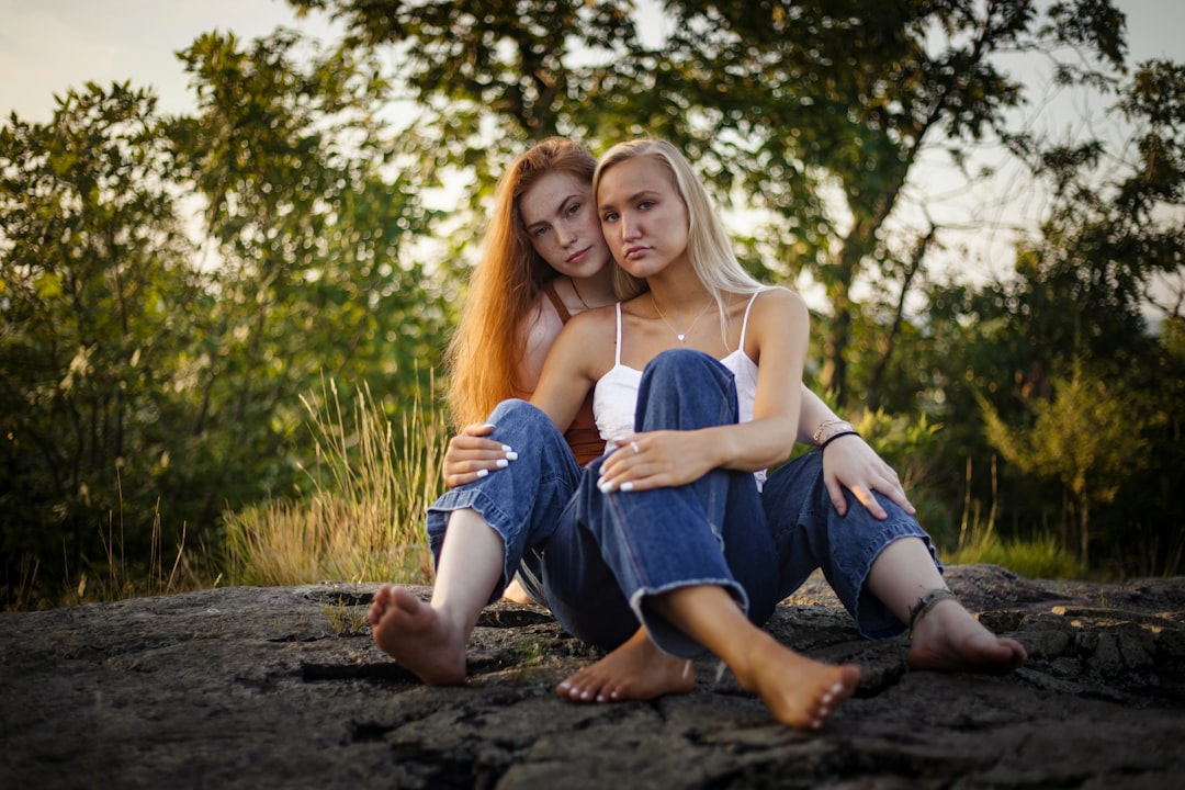 two women sitting on pavement