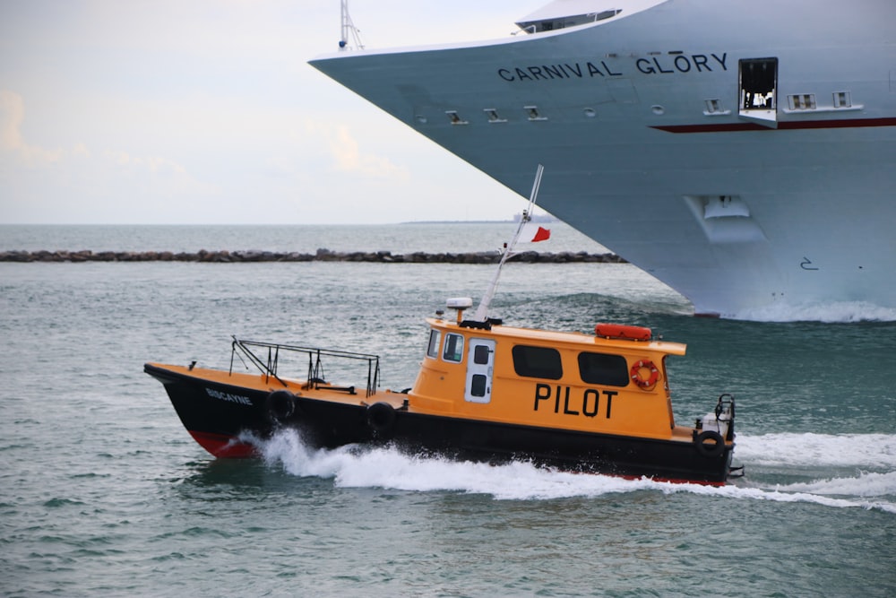 a yellow and black boat in the water and a large ship in the background