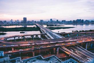 A city skyline at dusk with illuminated bridges and highways symbolizing infrastructure development.