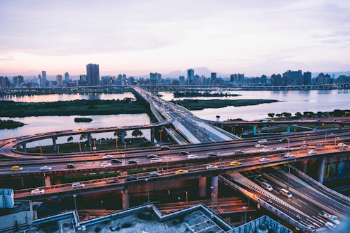 A city skyline at dusk with illuminated bridges and highways symbolizing infrastructure development.