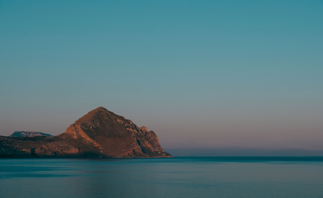 brown mountain beside seashore during daytime