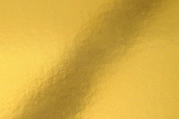 A sleek, abstract gold texture glowing softly against a deep obsidian background, evoking mystery and prestige.