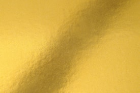 A textured surface with a gold metallic sheen, showcasing a gentle gradient of light and shadow across the material.