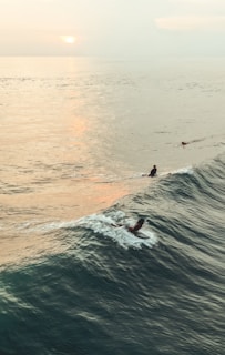 person surfing on body of water during golden hour