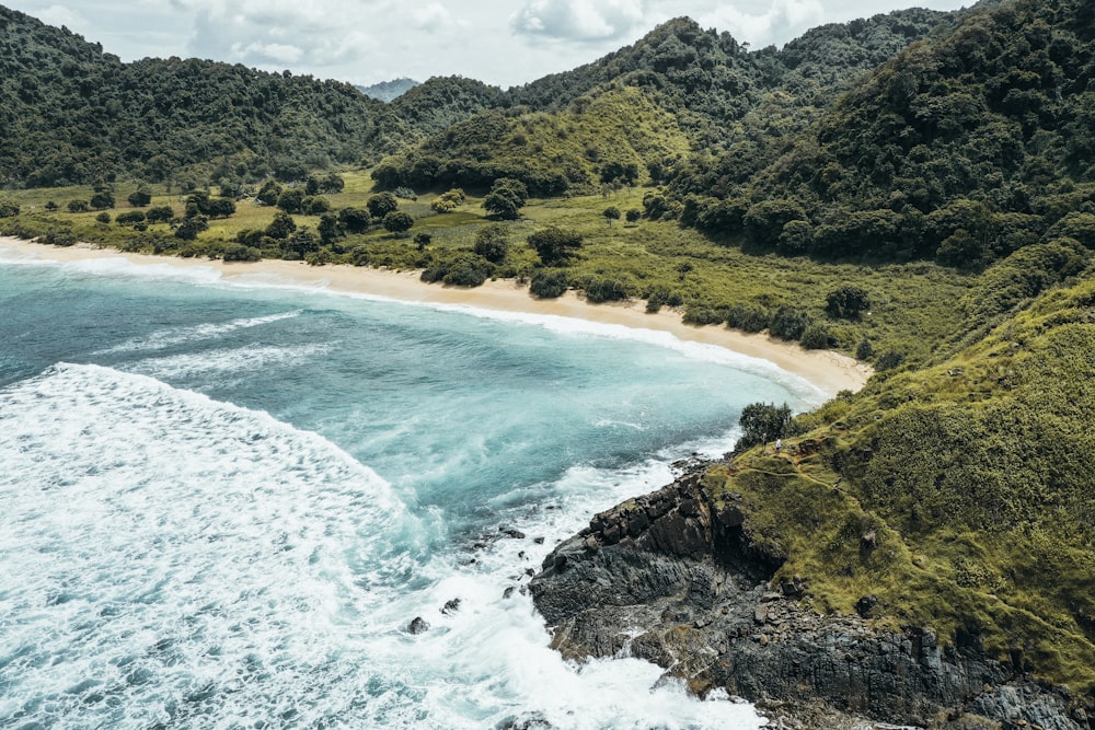 body of water near green mountains at daytime