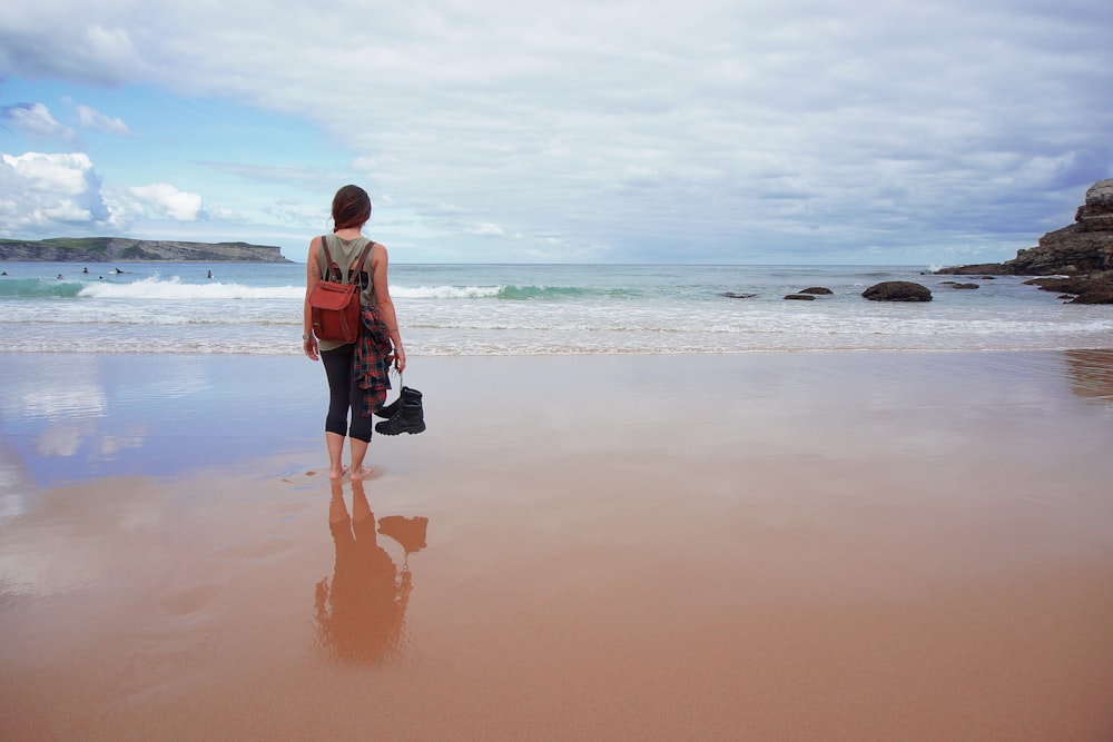 woman standing beside body of water during daytime