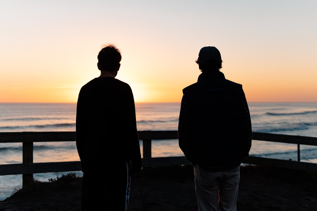two men standing beside sea
