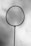 A silhouetted tennis racket is held against a cloudy sky, with the strings clearly visible.