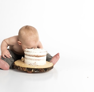 kid sitting beside round cake close-up photography