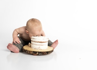 kid sitting beside round cake close-up photography