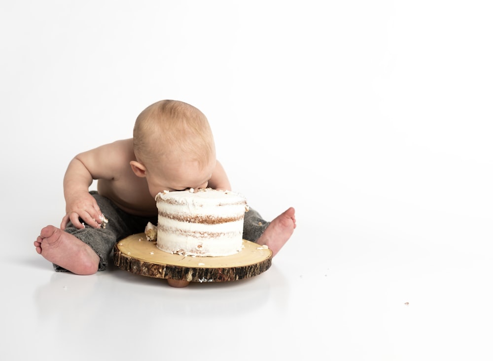 Niño sentado al lado de la fotografía de primer plano de la torta redonda