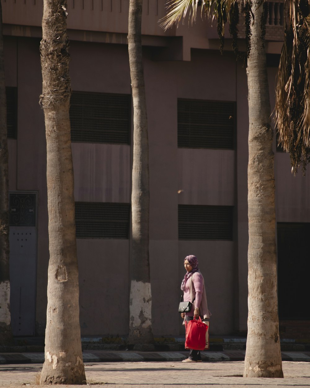 woman carrying bag while standing near trees