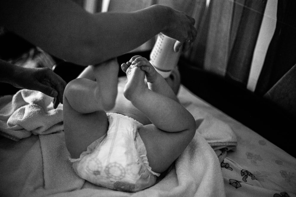 a black and white photo of a baby on a bed