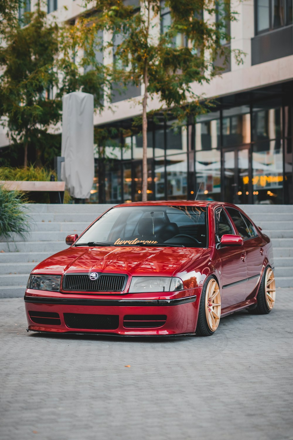 red sedan on concrete surface in front of stairs