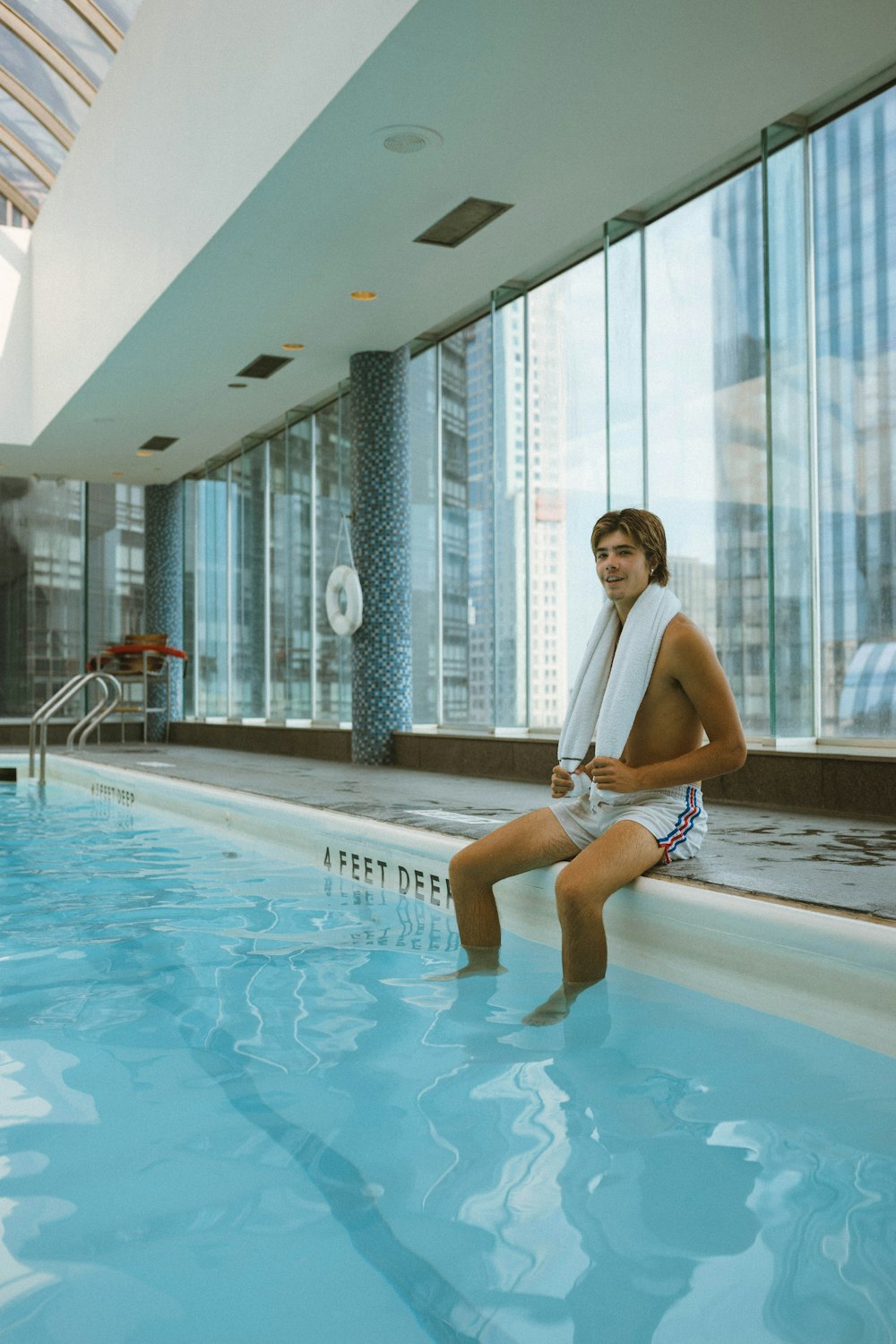 man wearing white shorts sitting besides pool