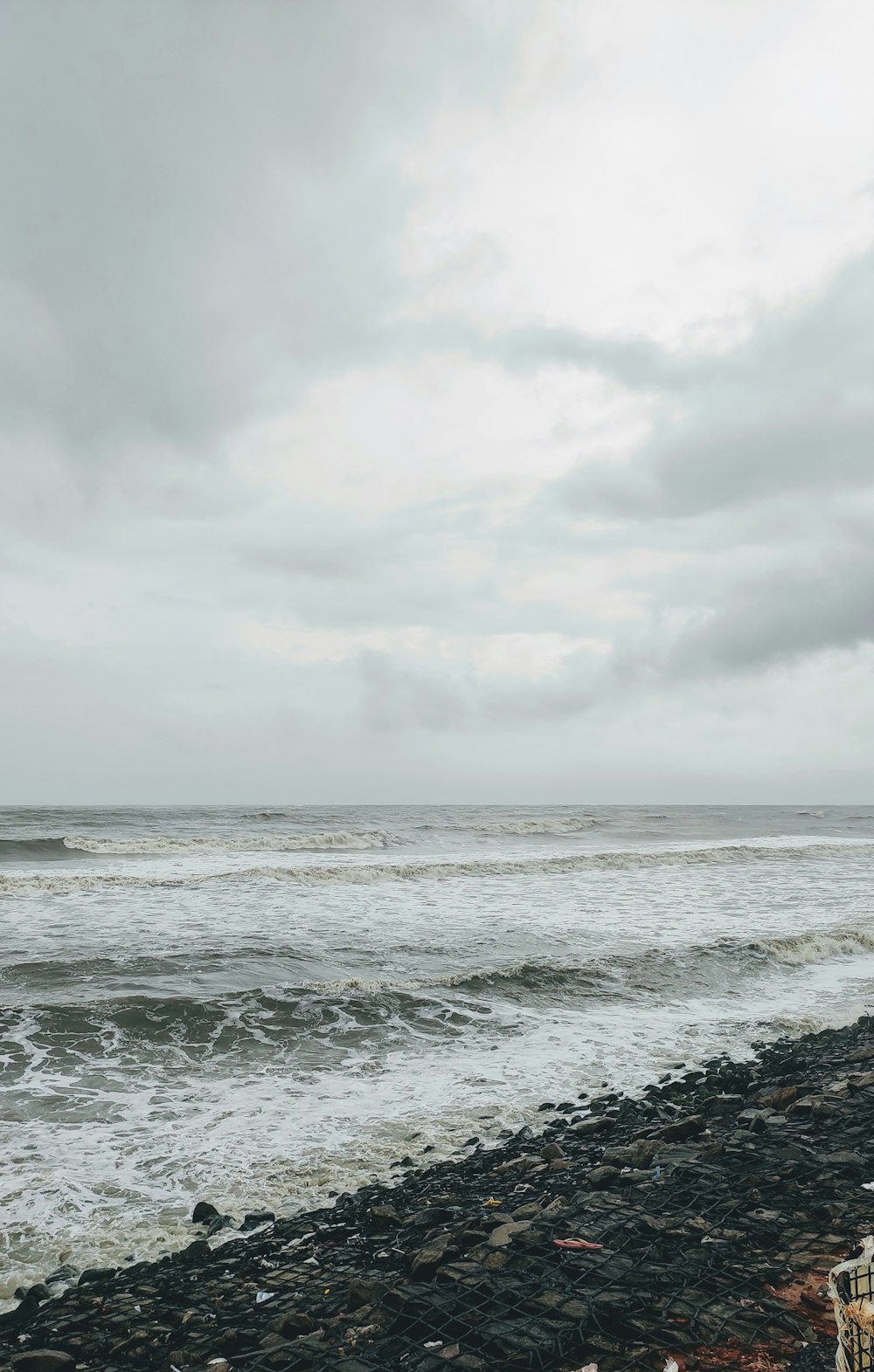 a person standing on a rocky beach next to the ocean