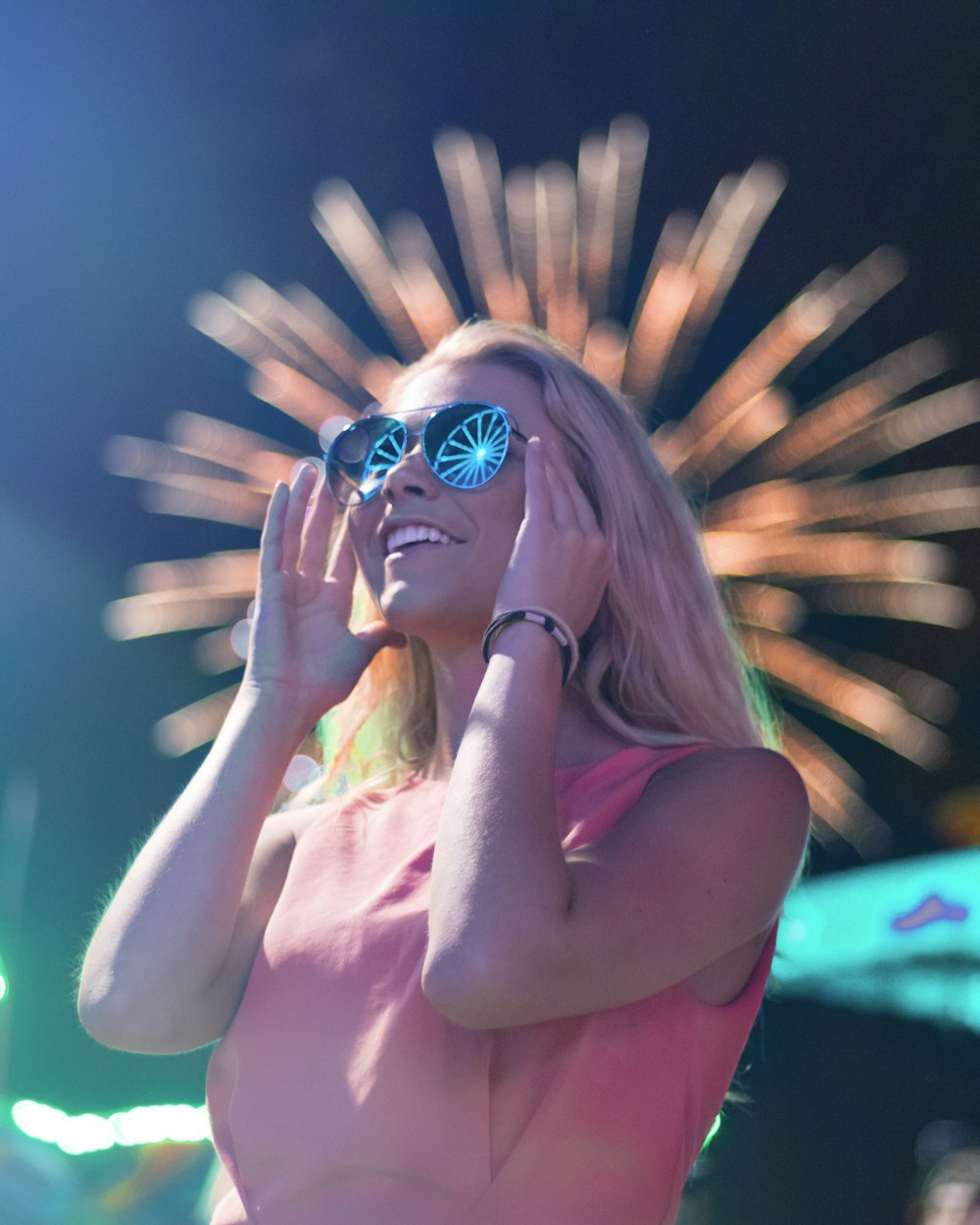Frau mit Sonnenbrille schaut nachts auf Feuerwerk