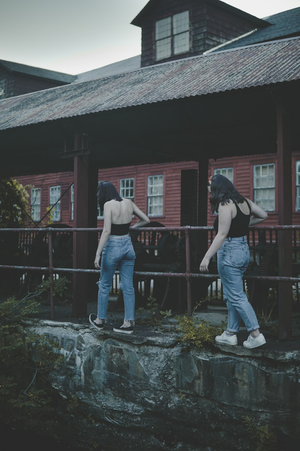 two women walking beside handrail and building