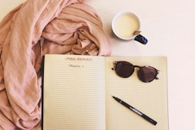 An open notebook with a pen, next to a healthy smoothie and fitness tracker