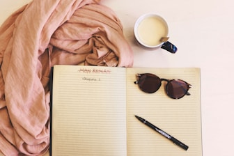 An open notebook with a pen, next to a healthy smoothie and fitness tracker