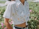White cotton shirt featuring a delicate floral embroidery design on the chest pocket.