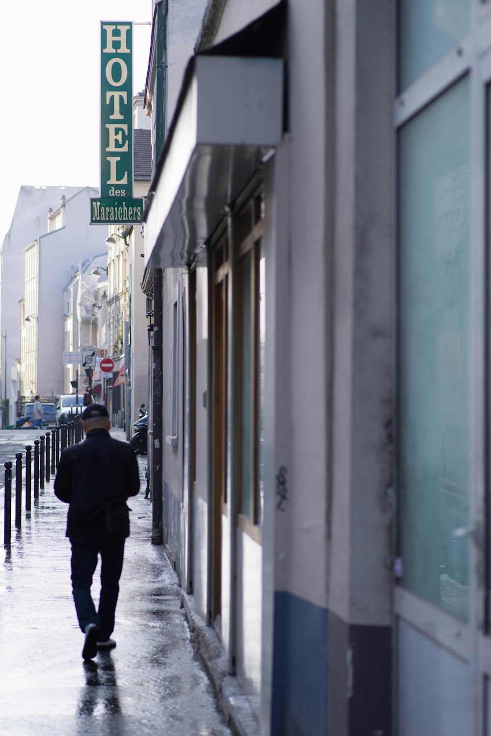 man walking on sidewalk beside building during day