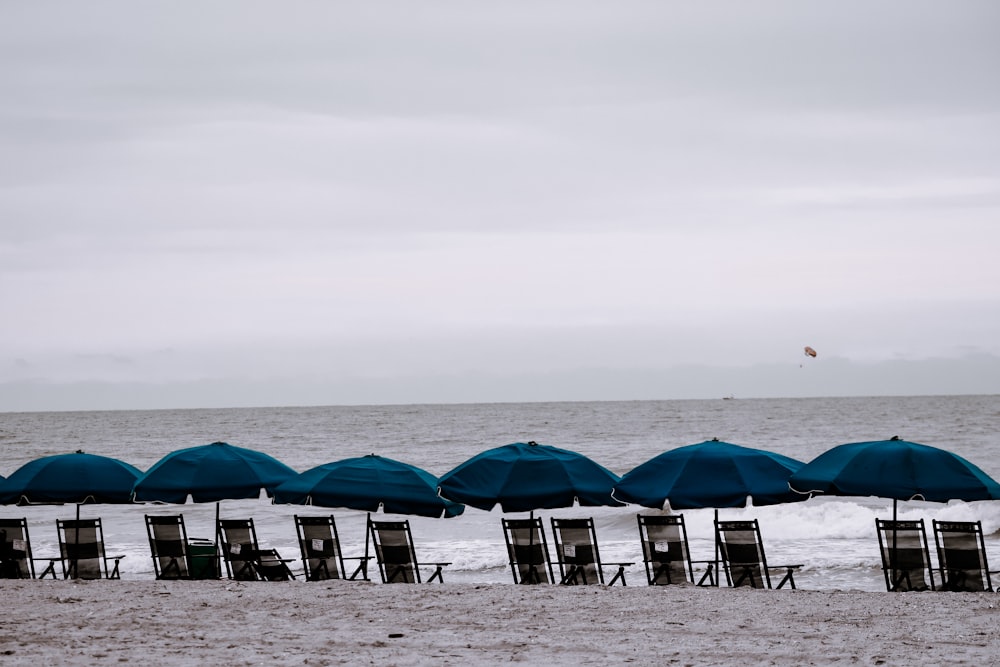teal beach umbrellas and beach lounges during daytime