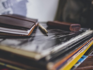 A stack of open books with a pen resting on top, symbolizing writing and creativity.