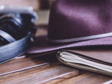 An open notebook with handwritten notes and a vintage camera resting beside it on a wooden table.