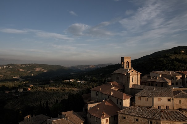 A panoramic view from a hilltop overlooking a picturesque village surrounded by rolling hills.