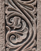 Intricate stone carving features swirling floral and abstract patterns, showcasing detailed craftsmanship with a weathered texture.